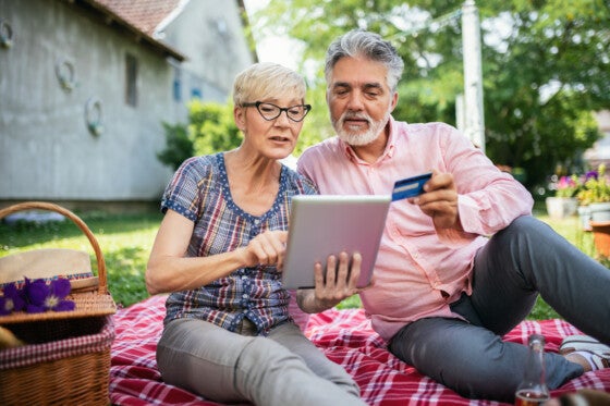 Older couple using credit card to buy online while on a picnic