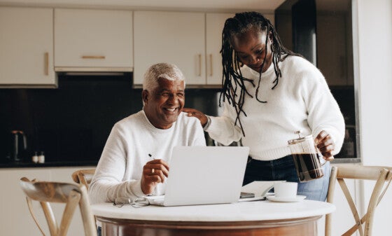 Supportive woman pouring her husband a cup of coffee in his home office. Happy mature woman encouraging her husband while he's working from home.