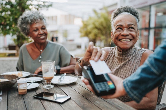 Senior woman with friend making credit card payment