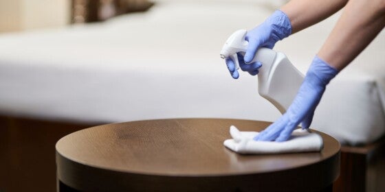 Cropped photo of maid spraying disinfectant on furniture while cleaning the room. Housekeeping and hygiene concept