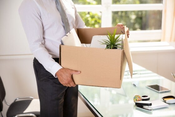 Midsection View Of A Businessman's Hand Holding Belongings In Cardboard Box