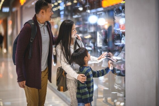 Curious young Chinese boy window shopping with parents at Harbour City Shopping Centre in Hong Kong.