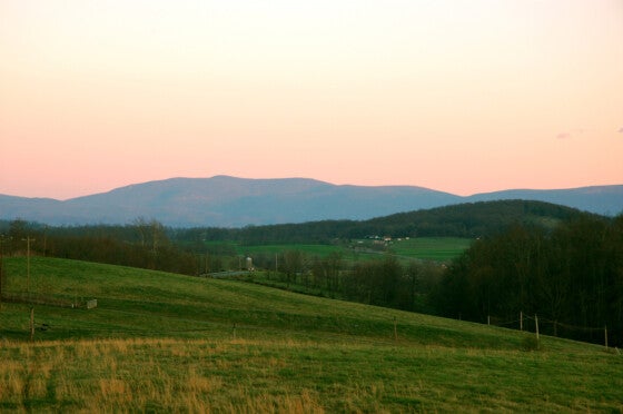 Rolling hills and mountain range in background during sunset.