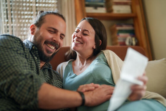 Expectant Couple looking ultrasound images of baby in living room