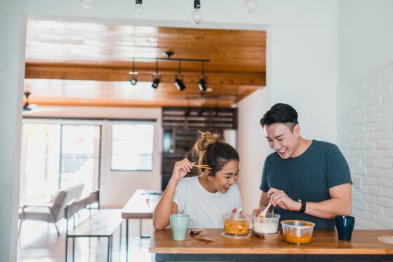 Asian couple eating noodles in domestic kitchen