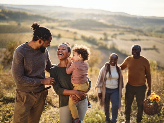 Happy black family talking while going on a picnic up the hill.