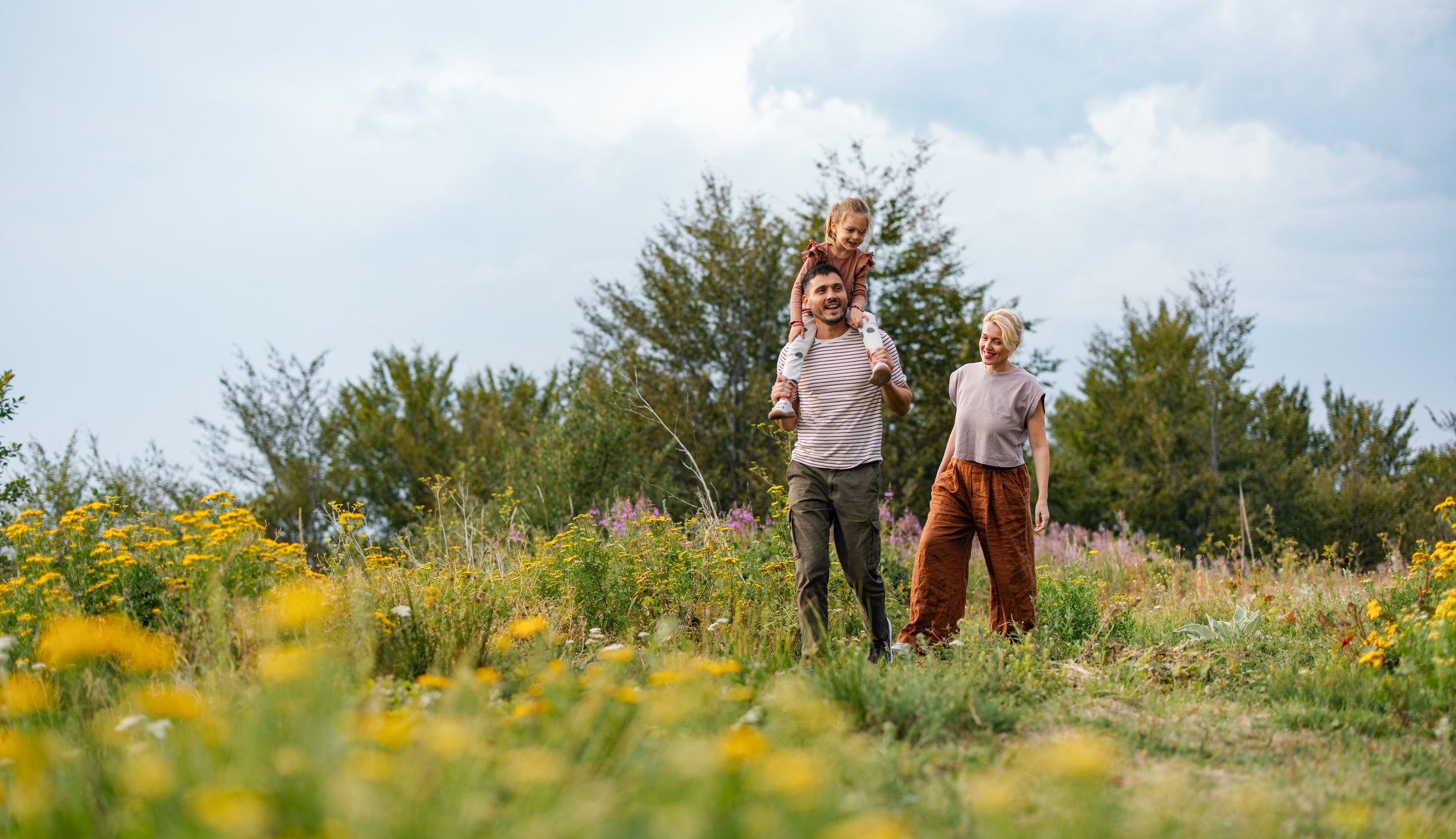 Happy Family Stroll Through a Vibrant Meadow on a Sunny Day